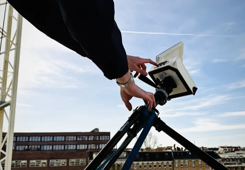 Hände justieren Kamera auf Stativ, Leipziger Stadtpanorama im Hintergrund